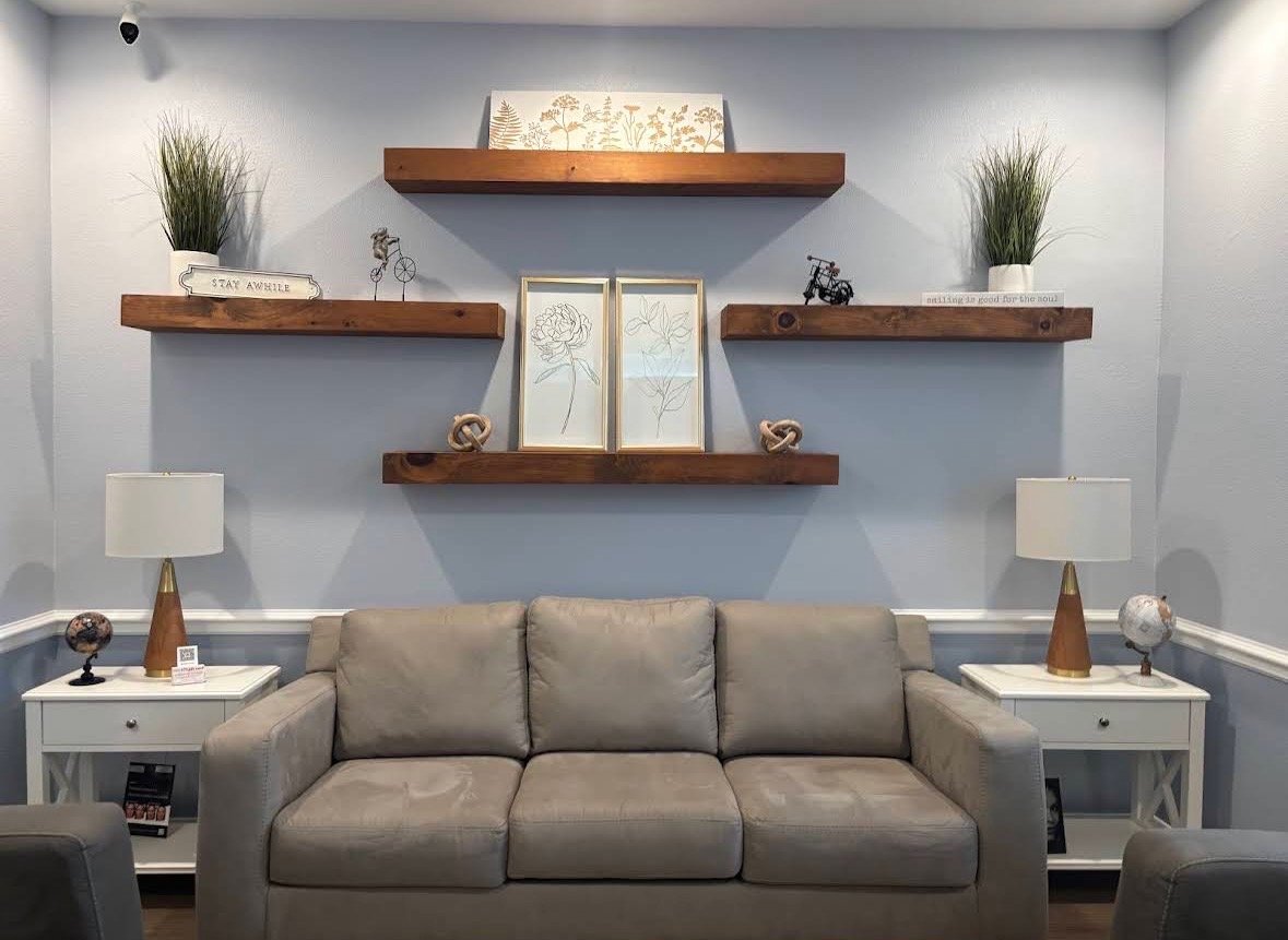 Liquid Love Med Spa lounge with floating wood shelves and a beige sofa